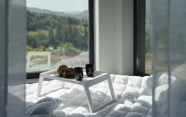 Breakfast table on white bed behind white curtains with mountains view