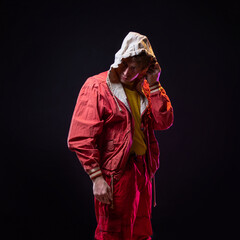 A young guy in a red youth jacket with a hood. Stylish outfit, modern style, photo on black