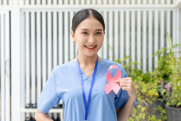 Asian Doctor holding pink ribbon smile positive emotional for supporting people to heal and fight to breast cancer. October breast cancer awareness month. Health care and insurance concept