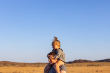 Toddler Riding On Father's Shoulders Against Blue Pilbara Sky