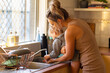 © Austockphoto - mother washing toddler's hands at kitchen sink
