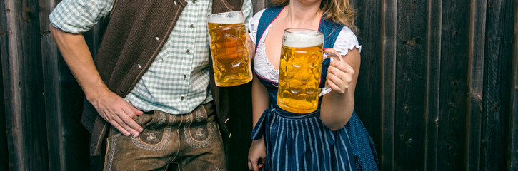 Oktoberfest, woman and man in Bavarian costume with beer mugs