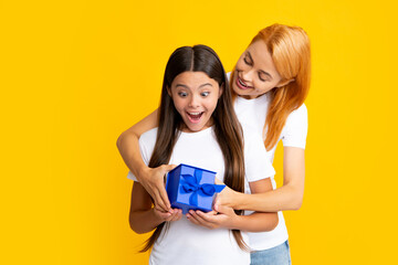 Canvas Print - Young teen girl giving gift box to her mother on color background. Happy family. Mother and daughter with present gift.