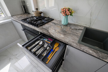 High angle closeup view to open drawer of grey and white modern domestic kitchen