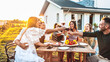 © Davide Angelini - Group of friends having fun at bbq outside dinner in home garden - Happy people cheering red wine sitting outdoor at dining table - Social gathering, youth, food and beverage concept