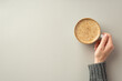 Leinwandbild Motiv Autumn concept. First person top view photo of young woman's hand in sweater holding cup of frothy coffee on isolated grey background with empty space