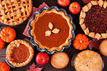 Poster - Collection of homemade autumn pies. Pumpkin, apple and pecan. Above view table scene on a dark wood background.