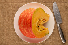 One Piece Of Ripe Organic Pumpkin With White Ceramic Dish On Jute Cloth, Macro, Top View.