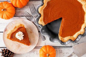 Poster - Slice of pumpkin pie with whipped cream topping. Top view table scene on a white wood background.