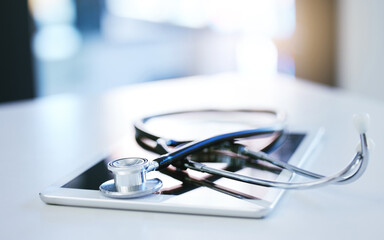 Poster - Digital tablet, stethoscope and telehealth consulting on table in empty hospital, wellness and medicine insurance room. Zoom on medical equipment, healthcare research and internet technology for help