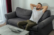 © Lilu - Young smiling man relaxing working with laptop and video conference at home. Young creative man looking at screen message using smartphone.Work from home