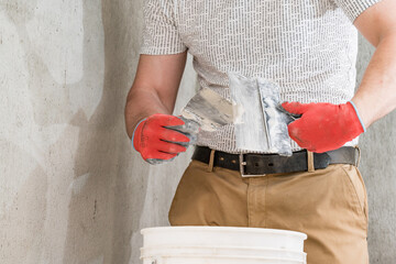 A man with a small spatula applies lime plaster on a large spatula, lime plaster on the walls and ceiling.