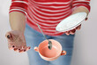 A female in red and white stripy shirt dropping teacup with tea and spoon, selective focus