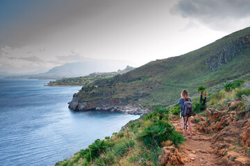 Famous natural reserve Zingaro, province of Trapani, Sicily, Italy, Europe. Young girl with a backpack on the trail. Riserva naturale dello Zíngaro, Sicilia, Italia