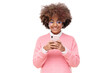 © Damir Khabirov - African american smiling teenage girl with afro hairstyle holding smartphone with both hands, chatting with friend, using social media app