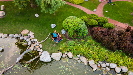 Wall Mural - aerial drone view of a African American couple sitting happily together in a Japanese garden during late evening. its peaceful area to be in surrounded by amazing botany 