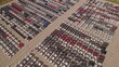 Aerial view of car storage or parking lot new unsold EV cars. Vehicle automaker and manufacturer parking facility. Low carbon footprint EV electric cars are ready for further distribution.