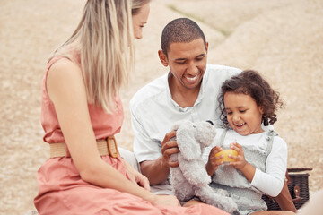 Interracial family, beach travel and summer fun with child enjoying bonding time with mother and father during a picnic on rocks. Happy man and woman playing on vacation or holiday with cute daughter