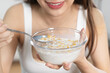 © Pormezz - woman eating a bowl of cereal with milk as breakfast in morning
