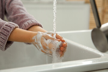 Wall Mural - Little girl washing hands with liquid soap at home, closeup