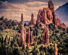 Surreal  Rock Pinnacles With Red Rock Sand Stone Towers Surrounded By Scrub Oak, Pine Trees And Cedar Trees And A Puffy Cloud Sky In A Beautiful Natural Location With Clear Blue Sky