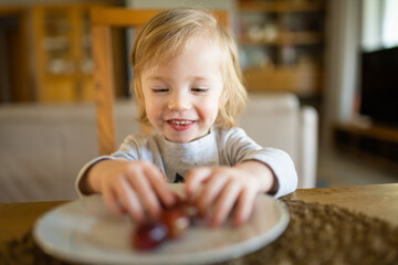 Wall Mural - Cute little toddler boy eating grapes at home. Fresh organic frutis for infants.