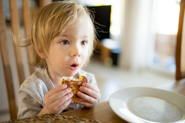 Wall Mural - Cute little toddler boy eating pancakes at home. Fresh organic food for infants.