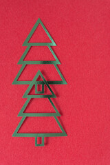 two stylized metallic foil christmas trees on red fabric and blank space