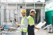 © thanmano - On a building site, Construction worker wearing protective gear holds a laptop and a blueprint, Working Safety at Workplace Concept