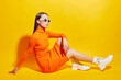 Fashion asian female model. Orange dress, white boots, sunglasses.