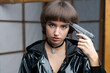 Portrait beautiful young caucasian woman in black patent suit with one hand holding pistol to her head, young sexy short hair girl with pistol looking at camera, pretty women are standing with pistol