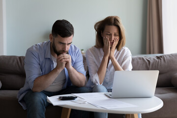 Wall Mural - Frustrated worried millennial husband and wife reading bankrupt message, blocked account notice, feeling concerned about overspent budget, lack of money, getting bad news, paying bills