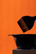 Hairdresser tools for dyeing hair. Applicator brush and tint mixing bowl on orange background
