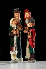 Christmas Figurine Of A Family Singing Christmas Carols Isolated On A Black Background
