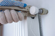 Leaking heating radiator. Plumber's hand with wrench repairs a leaking tap of a central heating pipe connection to a radiator. 