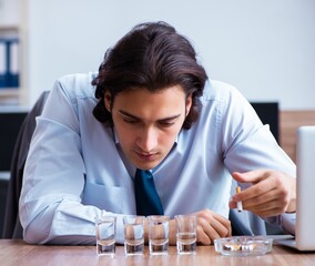 Poster - Male employee drinking vodka and smoking cigarettes at workplace