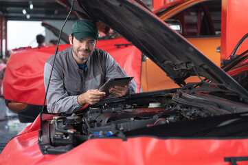 car service ,repair, maintenance concept - Arab auto mechanic man or Smith checking to the tablet at workshop warehouse, technician doing the checklist for repair machine a car in the garage