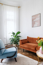 Bright Living Room In Apartment With Orange Couch, Light Blue Armchair