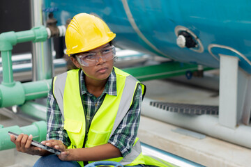 young woman engineer examining pipeline and looking digital tablet with professional in the factory,