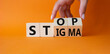 Stop and Stigma symbol. Concept words Stop and Stigma on wooden cubes. Beautiful orange background. Businessman hand. Business and Stop and Stigma concept. Copy space.