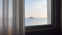 Small Ocean Island Seen Through A Window With Transparent Fabric Curtains