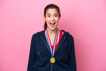 Wall Mural - Young Brazilian sport woman with medals isolated on pink background with surprise facial expression