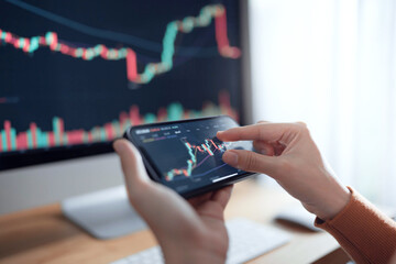 Closeup - Woman is checking Bitcoin price chart on digital exchange on smartphone, cryptocurrency future price action prediction.