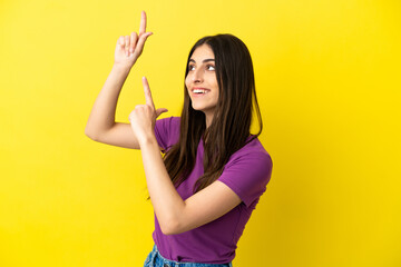 Wall Mural - Young caucasian woman isolated on yellow background pointing with the index finger a great idea