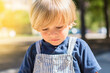 © Nanci - Portrait of an adorable 2 year old blond boy looking down, he is in the park on a sunny day with an out of focus background