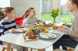 Teen children and their father talking during healthy breakfast at home in the morning before school