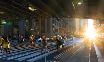 Wall Mural - Sunlight shining on people walking across a busy street crosswalk at Grand Central Station in Manhattan New York City