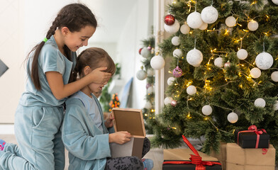 Wall Mural - Two cute beautiful girls near the Christmas tree with gifts. New Year. Christmas