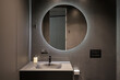Leinwandbild Motiv Illuminated round mirror in a dark bathroom interior