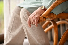 縁側の籐椅子に座るシニア女性の手